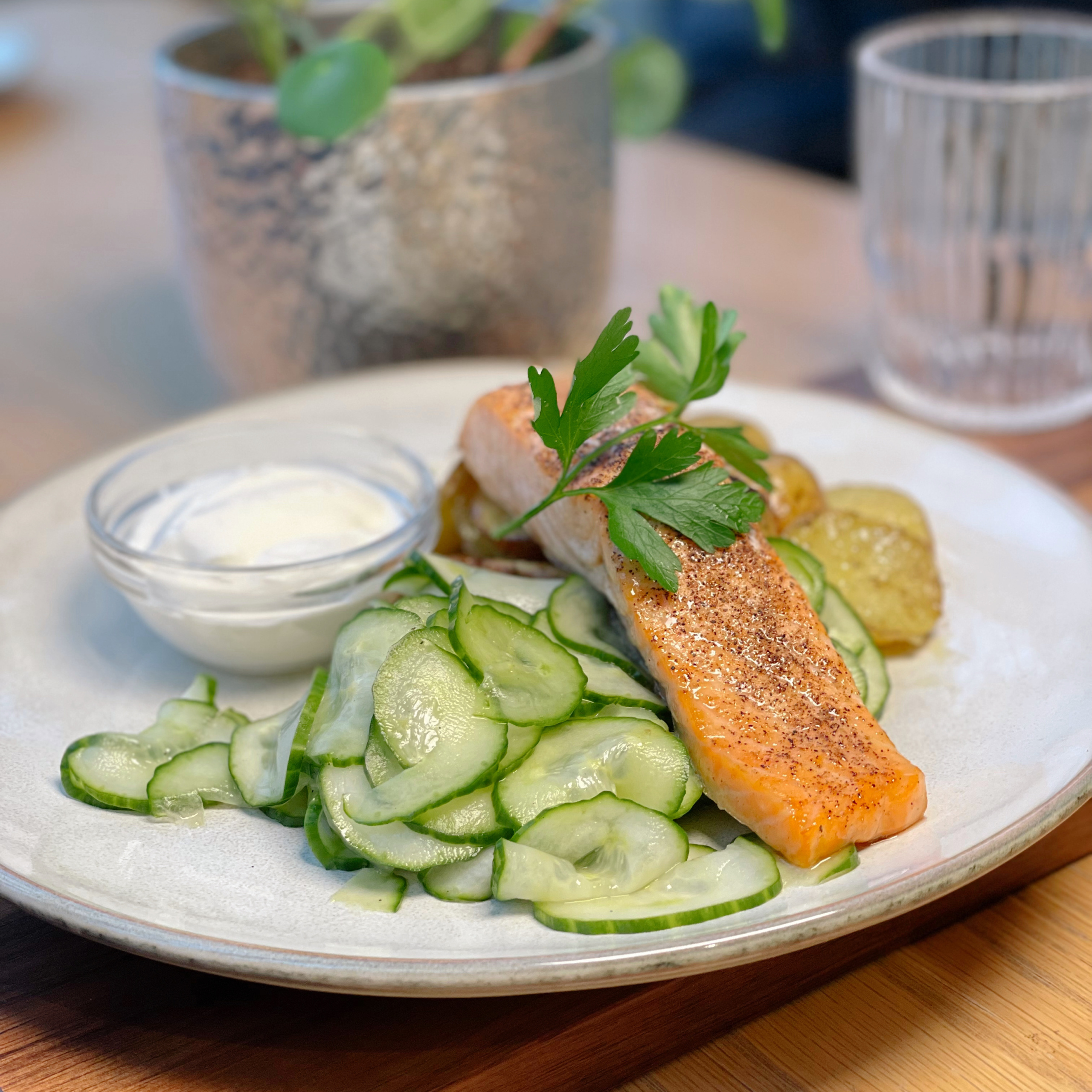 Tallerken med laks, poteter, agurk og rømme.
